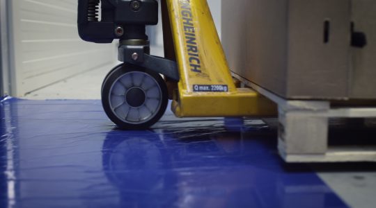 Heavy wheels crossing over a blue peel off mat.